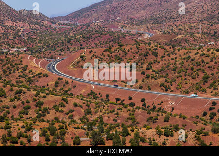 Une route moderne tisse à travers le terrain rouge entre Agadir et Marrakech. Banque D'Images