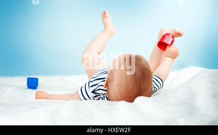 Bébé de 9 mois, couché dans le lit sur une couverture blanche Banque D'Images