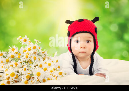 Mignon bébé couché dans le lit sur une couverture blanche en coccinelle hat Banque D'Images