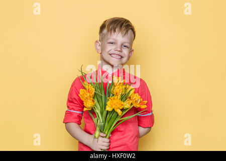 Peu de bel enfant avec chemise rose donne un bouquet de fleurs le jour de la femme, la Fête des Mères. Anniversaire. Le jour de la Saint-Valentin. Au printemps. L'été. Banque D'Images