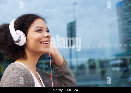 Close up portrait of a smiling young african american woman listening to music on headphones Banque D'Images