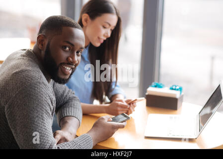 Young man and woman using smartphones at cafe Banque D'Images