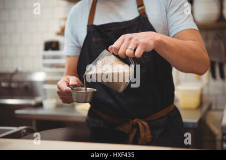 Portrait male chef pouring crêpe en mesure graduée en cuisine commerciale Banque D'Images