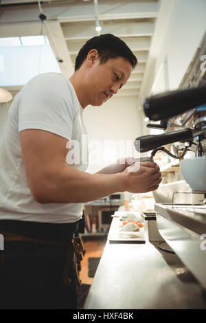 Vue de côté à l'aide d'une machine à expresso barista mâle in coffee shop Banque D'Images