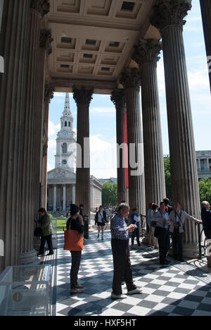 Les touristes à l'extérieur de l'entrée de la la Galerie Nationale avec St Martins dans le domaine de l'église distance derrière les piliers Banque D'Images