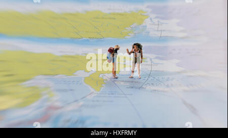 Focus sélectif de figurine miniature de lonely jeune voyageur avec sac à dos, debout sur une grande carte. Concept de voyage. Banque D'Images