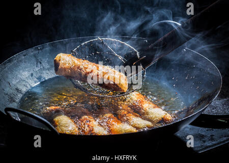 Les rouleaux de printemps faits maison à la poêle dans l'huile chaude Banque D'Images