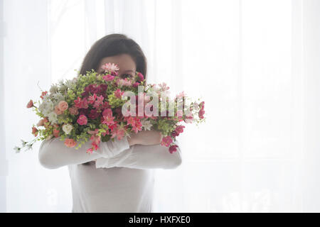 Jeune fille visage fermé avec un bouquet de fleurs rose, isolé sur fond blanc Banque D'Images