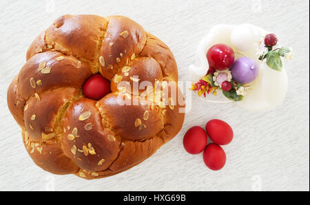 Pain traditionnel de Pâques ,tsoureki avec oeuf rouge au milieu des arbres , et les oeufs rouges et des bougies en forme d'oeufs Banque D'Images