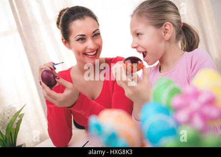Bonheur belle mère et fille peinture œuf de Pâques à la maison. Banque D'Images