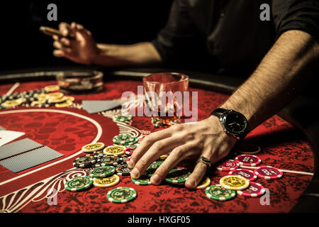 Close-up vue partielle de l'homme détenant des jetons de poker en étant assis à table dans le casino Banque D'Images