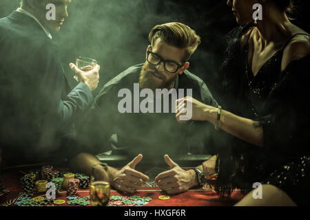 Portrait de l'homme jouant au poker alors que friends sitting on table in casino Banque D'Images