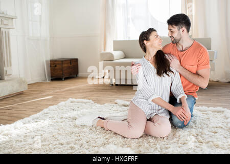 Happy young couple embracing on carpet and Banque D'Images