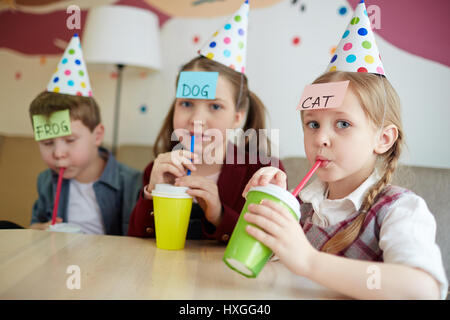 Les enfants assoiffés de boire de soude dans cafe et jouer Banque D'Images