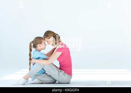 Fille souriante et mother hugging chaque autres on white Banque D'Images