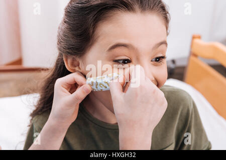 Vue rapprochée de la petite nurse putting girl le plâtre sur le visage du patient Banque D'Images