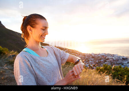 Close up portrait of woman smiling vérifiant sa montre pour l'occasion par le coucher du soleil Banque D'Images