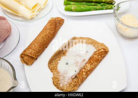 Le quinoa crêpes Préparation : l'ajout de sauce blanche à la quinoa crêpes Banque D'Images