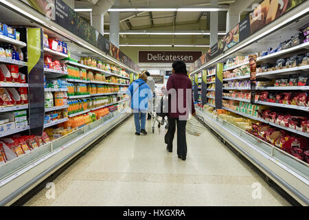 Les clients de l'allée au supermarché Tesco Food hall, Royaume-Uni Banque D'Images