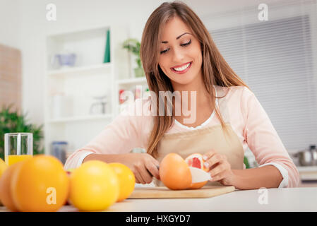 Jolie jeune femme en pamplemousse coupe cuisine. Banque D'Images