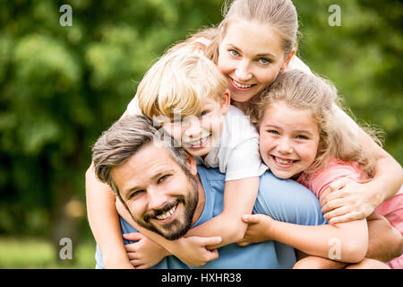 Famille heureuse avec deux enfants hugging ensemble en harmonie dans le jardin Banque D'Images