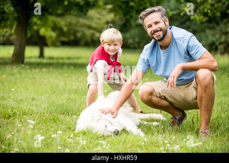 Garçon et père de famille avec chien jouant ensemble en été Banque D'Images