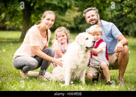 Heureux en famille avec enfants et chien ensemble au jardin en été Banque D'Images