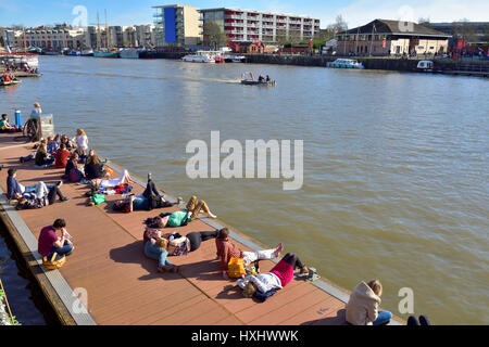 Chaude journée ensoleillée avec des gens assis sur dock flottant dans le centre-ville de Bristol docks Banque D'Images