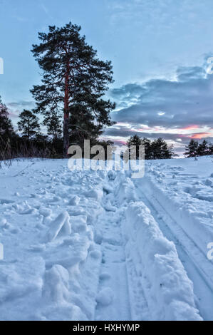 Une piste de ski passe au-dessus d'un lac sous le soleil. Les forêts et les arbres dans la neige et le gel à l'arrière-plan. Banque D'Images