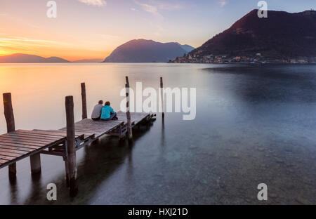 Un couple sur le quai d'Iseo, en face du Monte Isola, Province de Brescia, Lombardie, lac d'Iseo, Italie. Banque D'Images