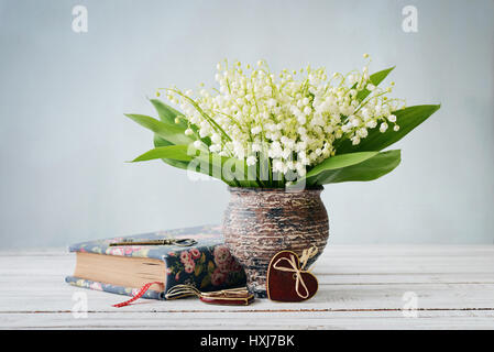 Bouquet de mai-lily avec réserve et coeur en céramique sur fond bleu Banque D'Images