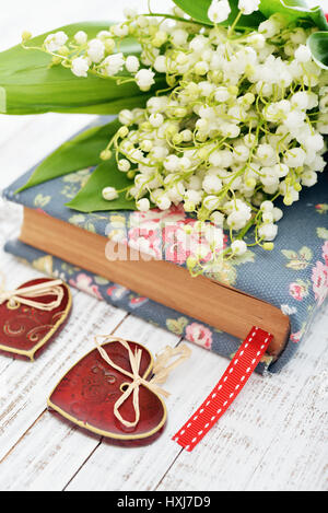 Bouquet de mai-lily avec livre libre et coeur en céramique sur fond de bois Banque D'Images