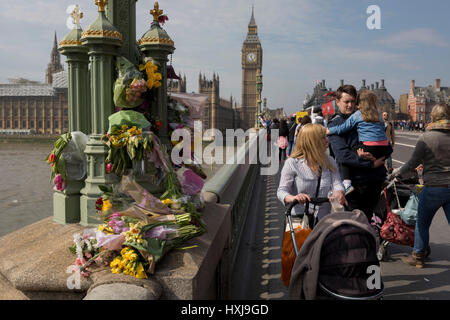 Londres, Royaume-Uni. Mar 28, 2017. Une semaine après l'attaque terroriste dans la capitale britannique, les londoniens et les visiteurs de la Grande-Bretagne regarder les monuments commémoratifs de la fleur à gauche sur le pont de Westminster (où les piétons ont été fauchés par une voiture) et à l'extérieur du palais de Westminster où la police armée garde maintenant l'emplacement où un policier a été tué. Crédit : Richard Baker/Alamy Live News Banque D'Images