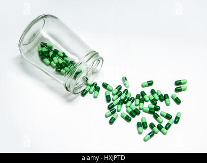 Capsule verte de médecine se déversait du verre bouteille Banque D'Images