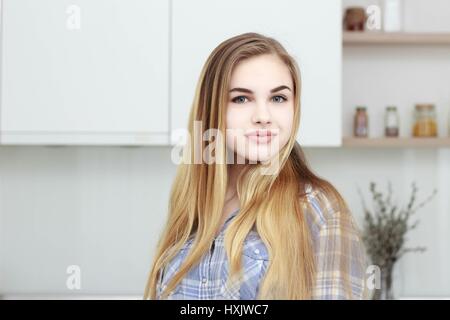 Belle jeune fille dans une chemise à carreaux bleu et jeans bleu se trouve dans la cuisine. Home intérieur Banque D'Images