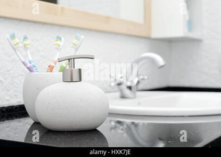 Distributeur de savon avec une brosse à dents dans le verre dans une salle de bains libre Banque D'Images