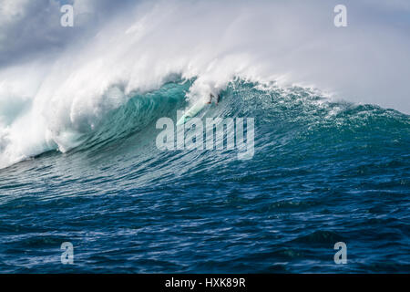 Un surfer efface sur un grand océan vague sur un récif extérieur spot de surf sur la côte nord d'Oahu, Hawaii Banque D'Images