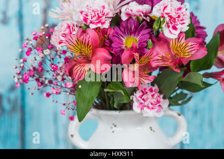 Bouquet de fleurs dans un vase bleu vintage avec fond de bois Banque D'Images