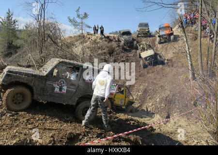 Off-road voiture ne peut pas monter, véhicule tout-terrain s'est coincé dans la boue d'un fossé, quatre disques durs à quatre roues sont en descente, co-pilote marche sur la boue Banque D'Images