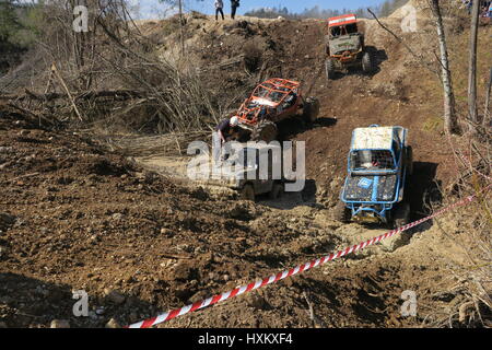 Pilote sur un capot de voiture est en fil d'acier de fixation, un hors-route voiture roule dans des tranchées boueuses, véhicule tout-terrain et d'un quatre roues motrices sont en descente Banque D'Images