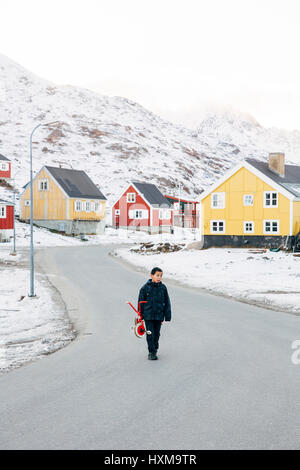 Un garçon portant un petit vélo rouge à Tasiilaq, qui est une ville dans la municipalité de Sermersooq dans le sud-est du Groenland. Le Groenland est une autonomouscount Banque D'Images