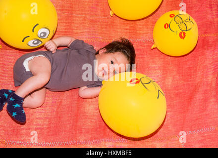 Mignon petit bambin entouré de ballons jaunes Banque D'Images