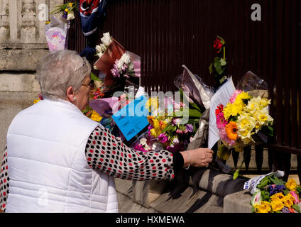 Westminster, London, UK. 27ème Mar, 2017. Une femme lisant un message de condoléances à gauche comme hommages sur les grilles du Parlement pour se souvenir de ceux de tuer Banque D'Images