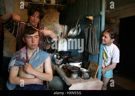 Lipovec village, région de Tver, Russie - Mai 7, 2006 : les agriculteurs russes de la famille dans sa maison paysanne, la coupe de cheveux de son fils en présence de son d Banque D'Images