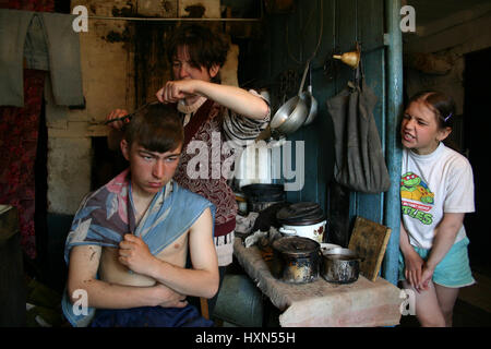 Lipovec village, région de Tver, Russie - Mai 7, 2006 : les agriculteurs russes de la famille à son domicile, la mère prend son fils hairstyle, maison rurale. Banque D'Images