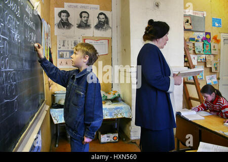 Podol village, région de Tver, Russie - Mai 5, 2006 : écolier a écrit à la craie sur le tableau noir à côté d'un enseignant de l'école de lire la tâche d'un schoolbo Banque D'Images