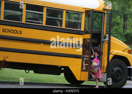 Petite fille sautant sur l'autobus scolaire Banque D'Images