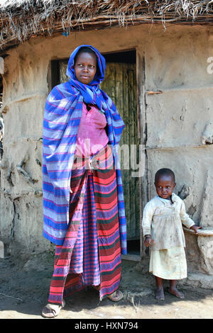 Meserani Snake Park, Arusha, Tanzanie - 14 Février 2008 : Jeune femme en robe drapée tribu Masaï, et une petite fille se tenait devant sa maison, Banque D'Images