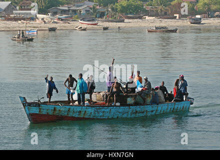 Zanzibar, Tanzanie - le 16 février 2008 : de nombreux hommes africains debout dans un bateau flottant bleu le long de la rive. Banque D'Images