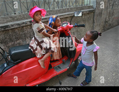 Zanzibar, Tanzanie - le 16 février 2008 : Groupe de plusieurs petites filles africaines jouent près de scooter rouge garée. Banque D'Images